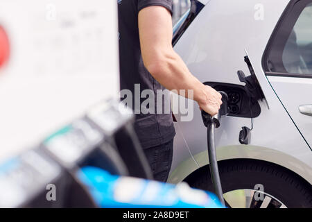 Nahaufnahme von Mann befestigen Sie das Netzkabel auf Umweltfreundliche Emissionsfreie Elektroauto Stockfoto