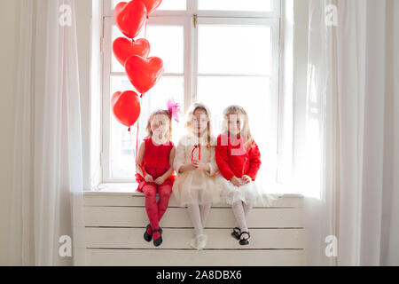 Drei schöne Mädchen mit Luftballons in rot und weiße Kleider an der Partei Stockfoto