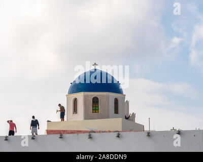 1. November 2019 - Santorini, Griechenland. Ein Arbeitnehmer gilt Pflaster auf der traditionellen Santorini Kirche mit einem blauen Kuppel. Stockfoto