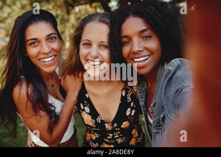 Gruppe von Happy diverse multirassischen Freundinnen ein selfie draußen im Park an einem sonnigen Tag lächelnd - Stockfoto