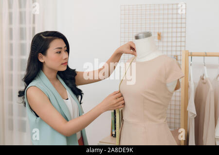 Junge asiatische Frau Modedesigner von Messungen an Mannequin in Ihrem Studio Stockfoto