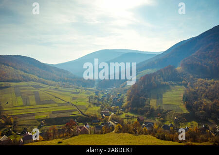 Üppig grüne bergige Landschaft auf einem nebligen Tag mit Dorf, eingebettet in einem Tal in malerischer Landschaft Stockfoto