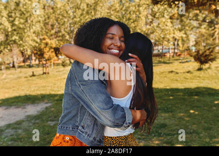 Zwei glückliche zärtlich diverse junge Frauen Freunde Umarmen im Park - zwei Freunde umarmen einander im Freien Stockfoto