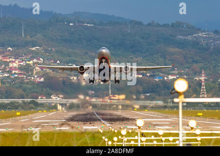 Blick auf die Landebahn des Flughafens und eine Take-off Ebene vor dem Hintergrund der Berge und Häuser Stockfoto