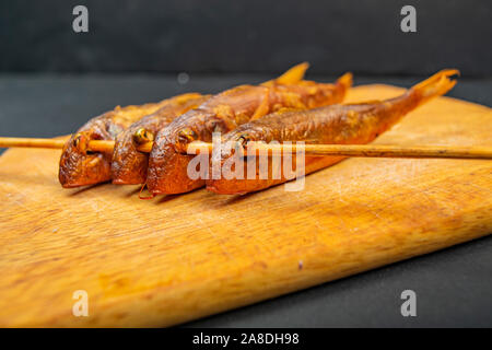 Getrocknete Meeräsche auf einem Holzbrett auf den Tisch. Fisch und Seafood Küche. Leckeren Snack Stockfoto