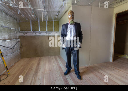 Seltsamer mann Geschäftsmann in Anzug und Gas schutz Maske in einem Raum unter der Renovierungsarbeiten. Stockfoto