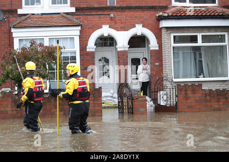 Feuer- und Rettungsdienst Mitglieder Spaziergang durch Hochwasser zu retten Bewohner in Doncaster, Yorkshire, als Teile von England von einem Monat im Wert von Regen in 24 Stunden ausgehalten, mit Kerben von Menschen gerettet oder gezwungen, ihre Häuser zu verlassen, andere über Nacht in einem Einkaufszentrum gestrandet, und Reiseplanung ins Chaos gestürzt. Stockfoto