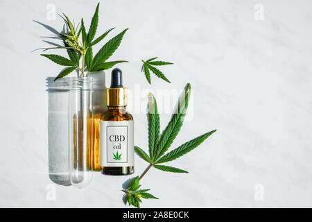 Glasflasche mit Cannabis Öl mit Label und ein Reagenzglas mit Hanf Blätter auf einem Marmor Hintergrund Stockfoto