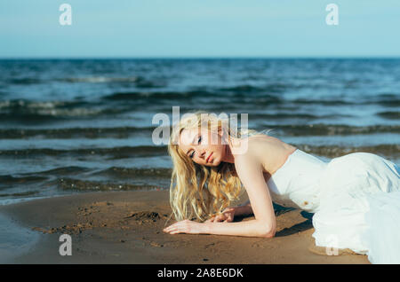 Porträt der jungen blonden Braut liegt auf Sand unter das Wasser, mit Blick auf die Kamera Stockfoto