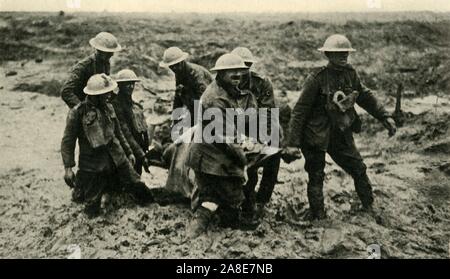 'Rote Kreuz arbeiten in Flandern Schlamm", den Ersten Weltkrieg, den 1. August 1917, (c 1920). "R.A.M.C. Stretcher - Träger bringen in den Verwundeten während der Vorauszahlung auf Passchendaele". Royal Army Medical Corps personal Kampf im Schlamm bis zu den Knien, um einen verletzten Mann in der Nähe von Boezinge während der Schlacht von Pilckem Ridge zu Sicherheit tragen. Die entsetzlichen Bedingungen auf dem belgischen Western Front waren durch starken Regen, die Meere der Schlamm verursacht. Von "Die Große Welt Krieg: Eine Geschichte", Band VII, herausgegeben von Frank eine Mumby. [Das Gresham Publishing Company Ltd., London, c 1920] Stockfoto