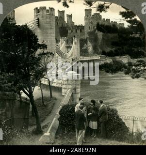 "Conway Castle, eine starke und edle mittelalterliche Festung, Conway, Wales', c 1930. 1820s Grad I Suspension Bridge von Thomas Telford zu Conwy Castle aufgeführt gebaut von Edward I. von 1283-1289 auf dem Fluss Conwy in Wales, ein UNESCO-Weltkulturerbe. Von "Tour der Welt". [Keystone View Company, Meadville, Pa., New York, Chicago, London] Stockfoto