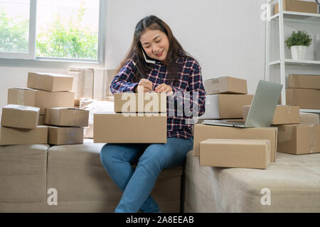 Junge Unternehmer, auf dem Sofa sitzen und arbeiten zu Hause. Entgegennahme der Aufträge von Kunden per Telefon und schriftlich Kunde Adresse Versand liefern auf Stockfoto