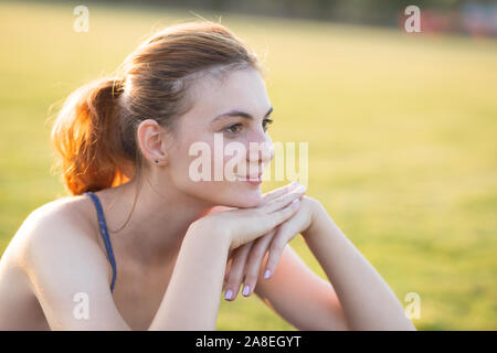 Close up Portrait von freundlich lächelnden jungen Mädchens mit Sommersprossen in ihrem Gesicht draußen in den sonnigen Sommertag. Menschlichen Ausdrucksformen und Emotionen Konzept. Stockfoto