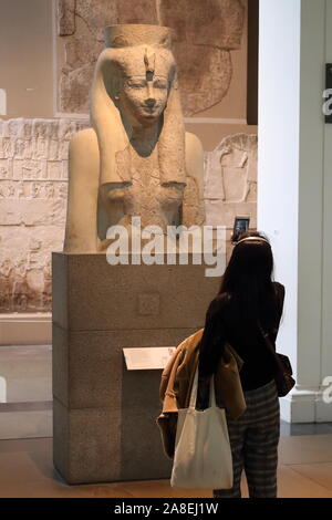 Eine Frau ist das Studium eine Büste der ägyptischen Göttin Hathor im Britischen Museum, London, UK Stockfoto