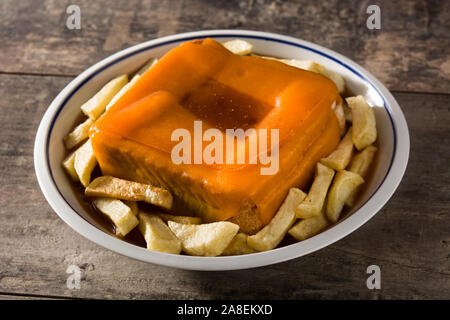 Typisch portugiesische francesinha Sandwich mit Pommes frites auf hölzernen Tisch Stockfoto
