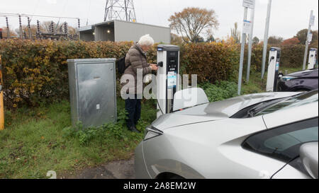 Frau stecken Nissan Leaf in Evolt Ladegerät des Elektrofahrzeugs, NEC, Birmingham Stockfoto