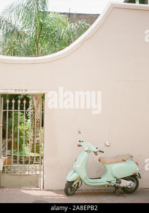 Eine alte Vespa Motorroller auf dem Bürgersteig vor einem ummauerten Garten im französischen Viertel geparkt, New Orleans, Louisiana Stockfoto
