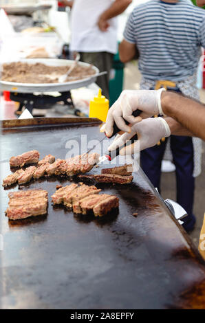 Der Mensch bereitet gebratenes Fleisch auf Street Food Festival. Traditionelles essen Fleisch Kugeln "Ici" auf Grill Stockfoto