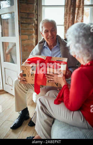 Happy Family open präsentiert auf Weihnachten Morgen. Lächelnd älterer Mann und Frau ihre Weihnachtsgeschenke austauschen Stockfoto