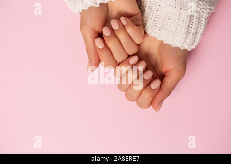 Nahaufnahme der schöne Hände, Nägel, zarte Maniküre auf rosa Hintergrund. Pflege, Schönheit, Wellness, salon Konzept, Ansicht von oben, kopieren Raum Stockfoto