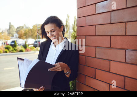 Seriöse Geschäftsfrau ist Lesen von Dokumenten beim Stehen im Freien. Stockfoto