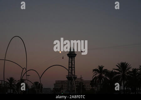 Silhouette von Barcelona Seilbahn Turm, Palmen, der Mond & Strukturen bei Sonnenuntergang Stockfoto