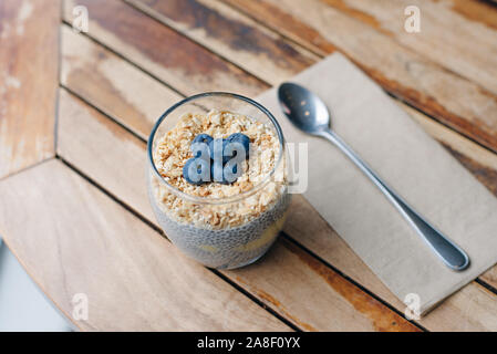 Blueberry yoghurt Parfait mit Müsli, Hafer und Chia Samen in ein Glas auf weissem Holztisch. gesundes Frühstück. Nach oben Schließen Stockfoto