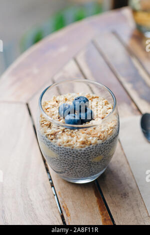 Blueberry yoghurt Parfait mit Müsli, Hafer und Chia Samen in ein Glas auf weissem Holztisch. gesundes Frühstück. Nach oben Schließen Stockfoto
