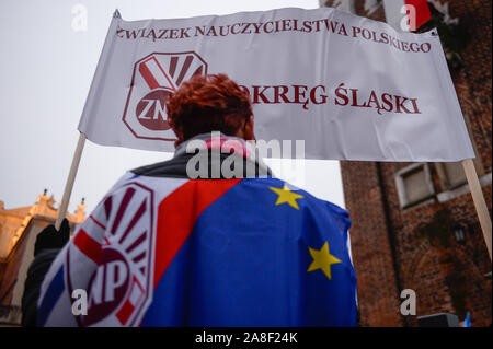 Eine polnische Lehrer trägt eine Weste mit der Fahne der Europäischen Union und der Polnischen Lehrergewerkschaft Logo als er Teil während eines Protestes anspruchsvolle für bessere Arbeitsbedingungen auf dem Hauptplatz. Lehrer die Forderung nach einer Erhöhung der Ausgaben für Bildung, Ausbildung statt der Erinnerung lernen, eine Erhöhung der Gehälter der Lehrer und pädagogische Fachkräfte, die Erhöhung der Autonomie der Schulen und Lehrer und Abbau der Bürokratie in den Schulen. Stockfoto