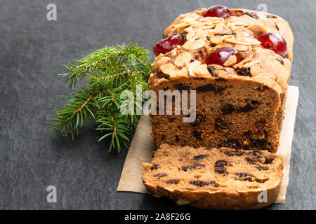 Gemischtes Obst Brot Kuchen mit mandelflocken auf schwarzen Stein Hintergrund Stockfoto
