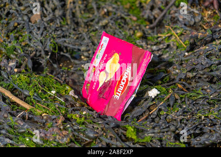 Scharfe Paket Verschmutzung am Strand in Seetang trinken sky Ocean Rescue gefangen Stockfoto