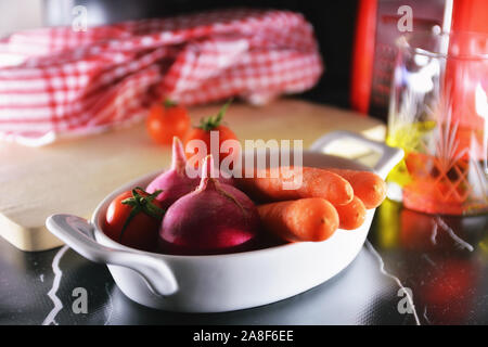 Salat Zutaten auf Schneidebrett in der Küche. Tomaten, rote Radieschen und Möhren. Stockfoto