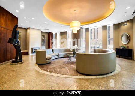 Eine moderne Lobby Wartebereich in einem Hochhaus in der Innenstadt von Chicago mit einem Wrap-around-Couch und Kronleuchter hängen von der Decke herab. Stockfoto