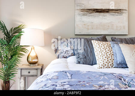 Ein Detail der Moderne, gemütliche Schlafzimmer mit dekorativen Kissen und Nachttisch mit Lampe Beleuchtung der Zimmer in einem Chicago Eigentumswohnung. Stockfoto