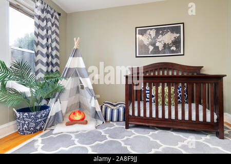 Ein Kind im Schlafzimmer mit einem dunklen farbigen Krippe und Tipi mit einem Kissen Lagerfeuer im Inneren. Stockfoto