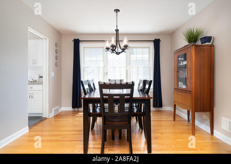 Ein kleines Esszimmer mit einer langen Tafel sitzen vor einem Fenster und helle Holzböden. Stockfoto
