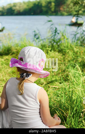 Ein kleines Mädchen ruht am Fluss Stockfoto