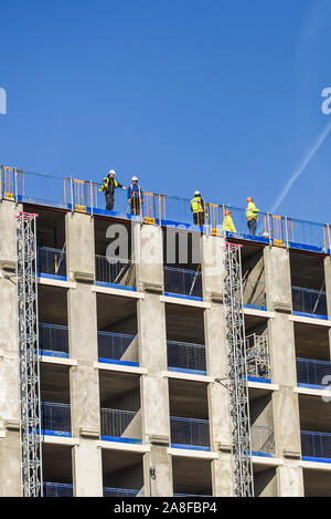 Handwerker stehen auf dem Dach eines riesigen Hochhauses Hilton Hotel Entwicklung als Kranführer, Treiber neue Teile des Gebäudes entlädt, Struktur Stockfoto