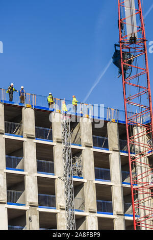 Handwerker stehen auf dem Dach eines riesigen Hochhauses Hilton Hotel Entwicklung als Kranführer, Treiber neue Teile des Gebäudes entlädt, Struktur Stockfoto