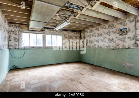 Die Zimmer eines verlassenen Hauses. Gruselige alte Tapeten an den Wänden mit grüner Farbe auf der Unterseite. Stockfoto