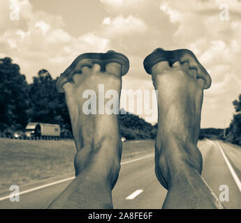 POV, Yoga toe Krankentragen mit angehobenen Füßen auf dem Armaturenbrett sind für die reisende Passagier in RV, nach unten gehen, ein Florida Highway in Schwarz und Weiß Stockfoto