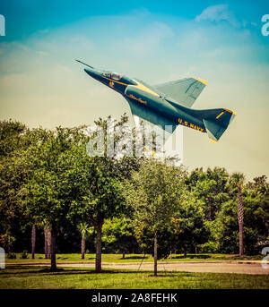 Ein tief fliegenden vintage US Navy Blue Angels Flugzeug Banking über die Baumkronen in den USA Stockfoto