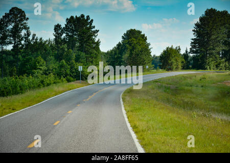 Eine gewundene leeren Asphalt Autobahn durch Pinien im ländlichen Süden von Mississippi, USA führenden Stockfoto