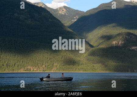Zwei Personen in einem Motorboot in Kootenay See, mit den Bergen der Purcell Wildnis Conservancy im Hintergrund, British Columbia, Kanada. Stockfoto