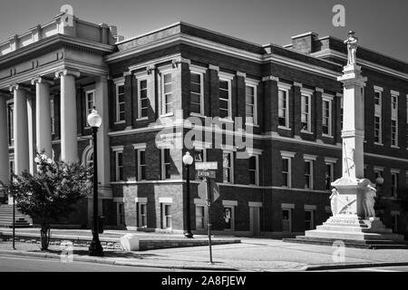 Ein hohes Marmordenkmal mit einer Skulptur eines konföderierten Soliders auf der Spitze steht neben dem Forrest County Courthouse in Hattiesburg, MS, USA, in B&W Stockfoto