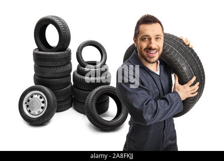 Mechaniker mit einem Fahrzeug Reifen mit Haufen von Reifen hinter ihm isoliert auf weißem Hintergrund Stockfoto