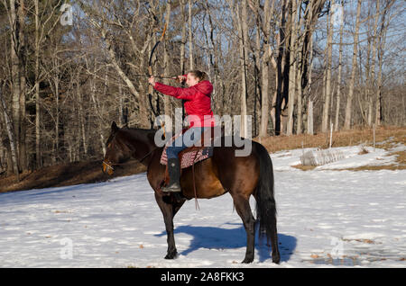 Junge Frau schießt Bogenschießen zu Pferd. Quarter Horse und der Bogenschütze praktizieren AIM, Maine, USA Stockfoto