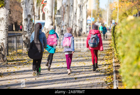 Kinder gehen auf dem Bürgersteig mit einem Spaß Unternehmen zur Schule Stockfoto