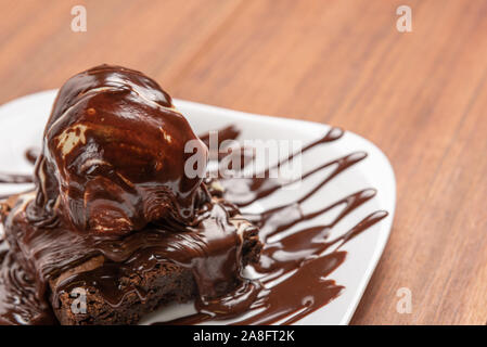Chocolate Brownies mit Vanilleeis und chocolatel Sirup auf Holz- Hintergrund isoliert Stockfoto