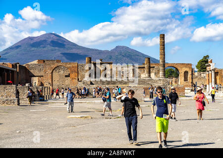 Touristen, die in das Forum der antiken Stadt Pompeji und Vesuv in der Ferne. Pompei, Kampanien, Italien, Oktober 2019 Stockfoto